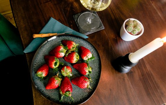 Strawberries and white wine on wooden table in restaurant